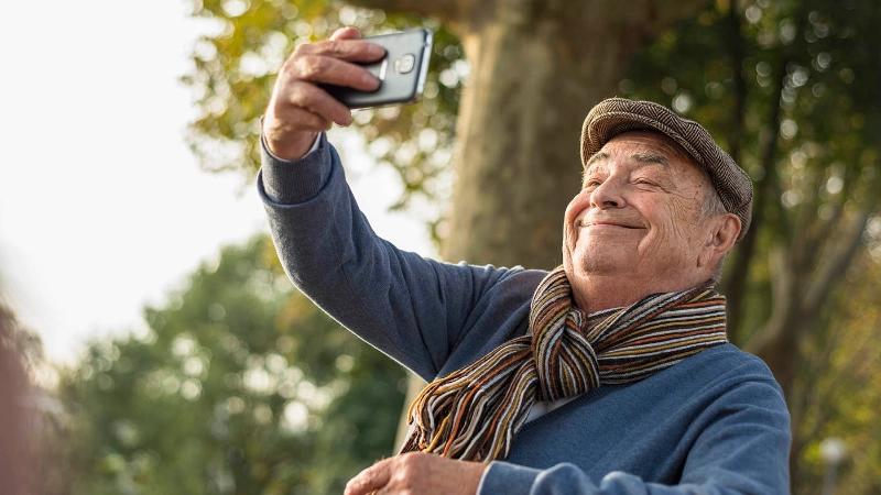 Ein älterer Herr macht ein Selfie mit dem Smartphone.